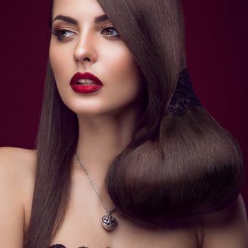 Pretty girl with unusual hairstyle, bright makeup, red lips. Beauty face.  Picture taken in the studio on a red background.